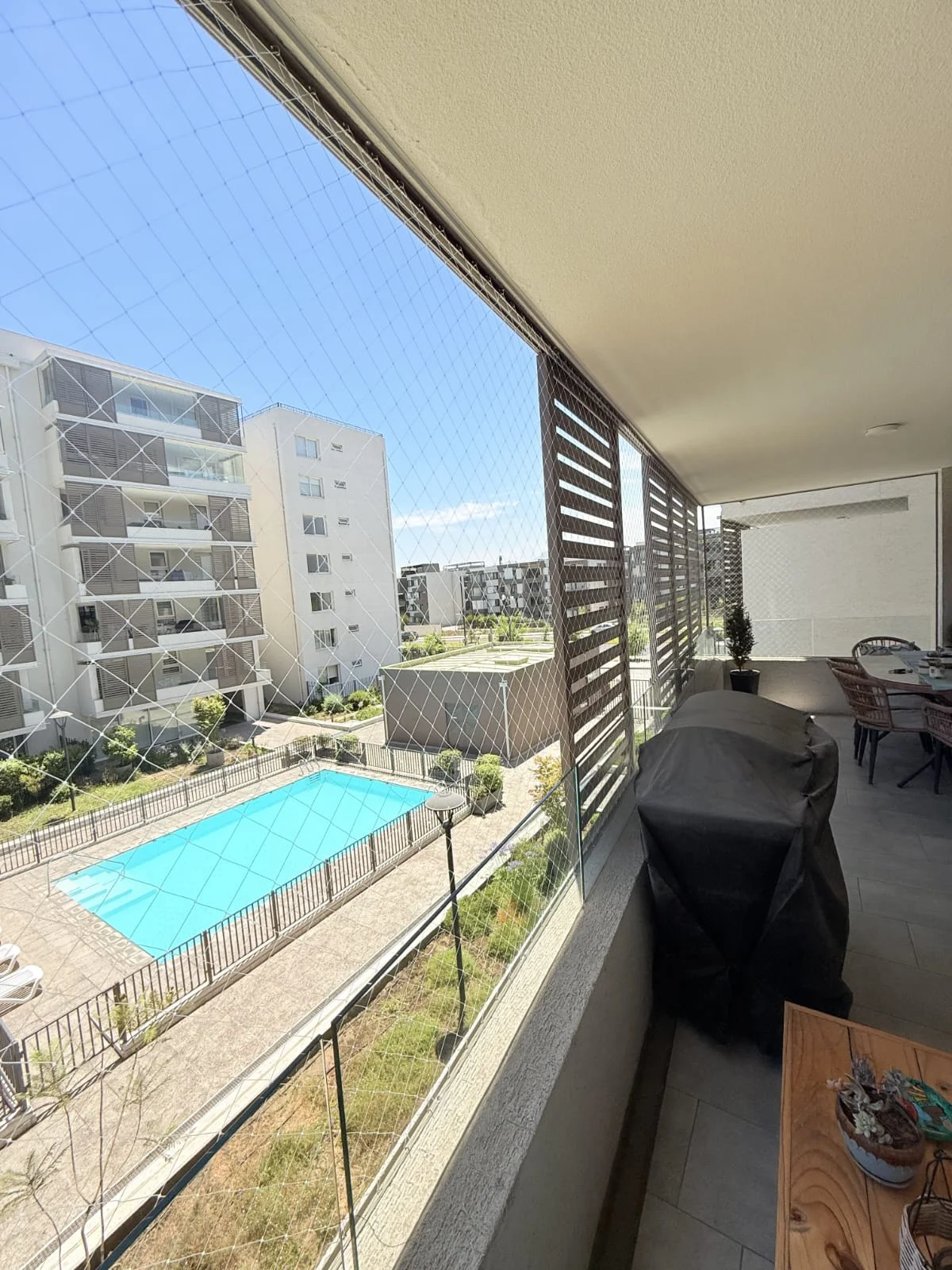 Balcón residencial con malla de seguridad y edificios al fondo