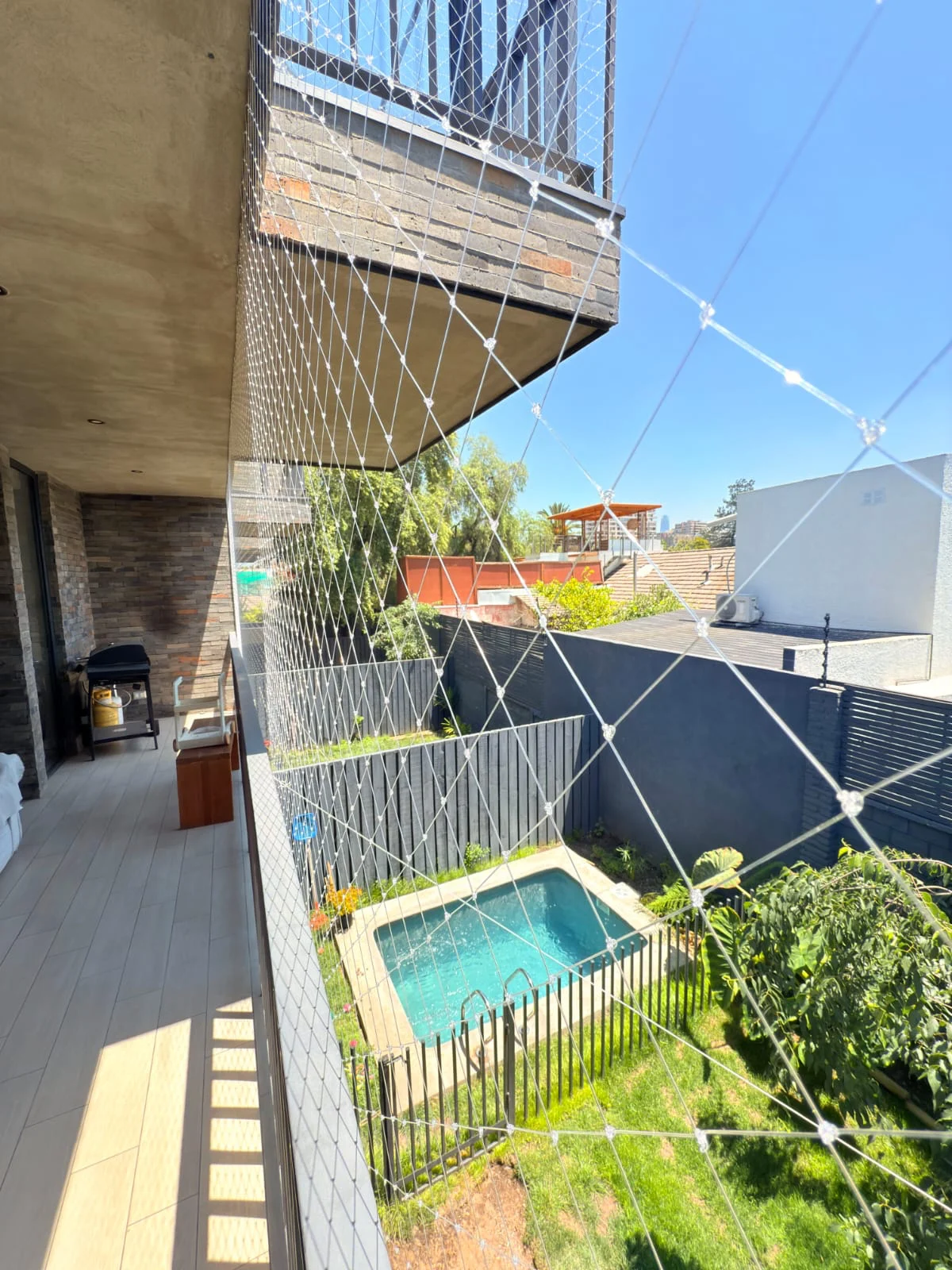 Balcón con malla y piscina en el nivel inferior
