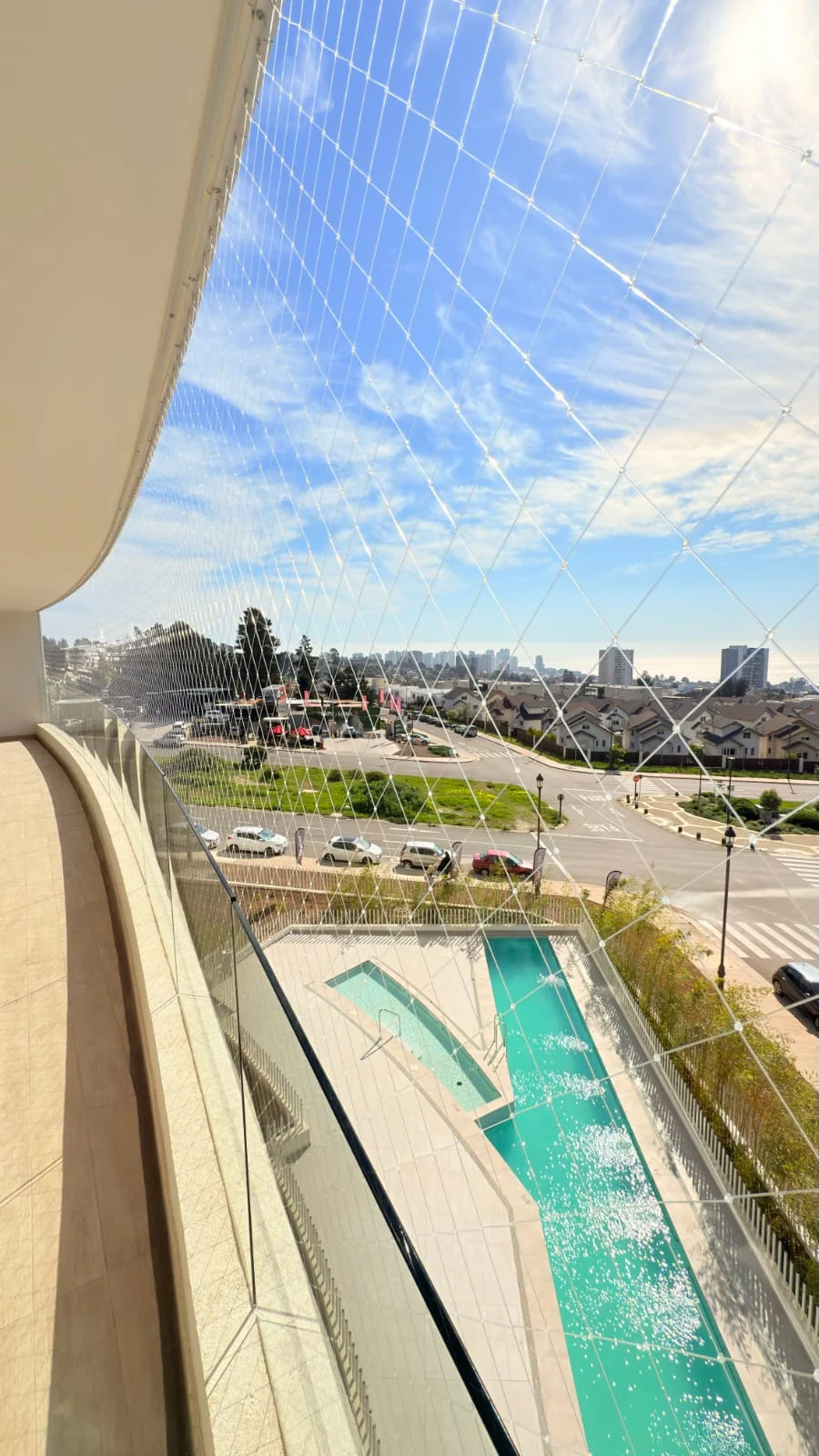 Malla instalada en un balcón con vista a edificios y piscina