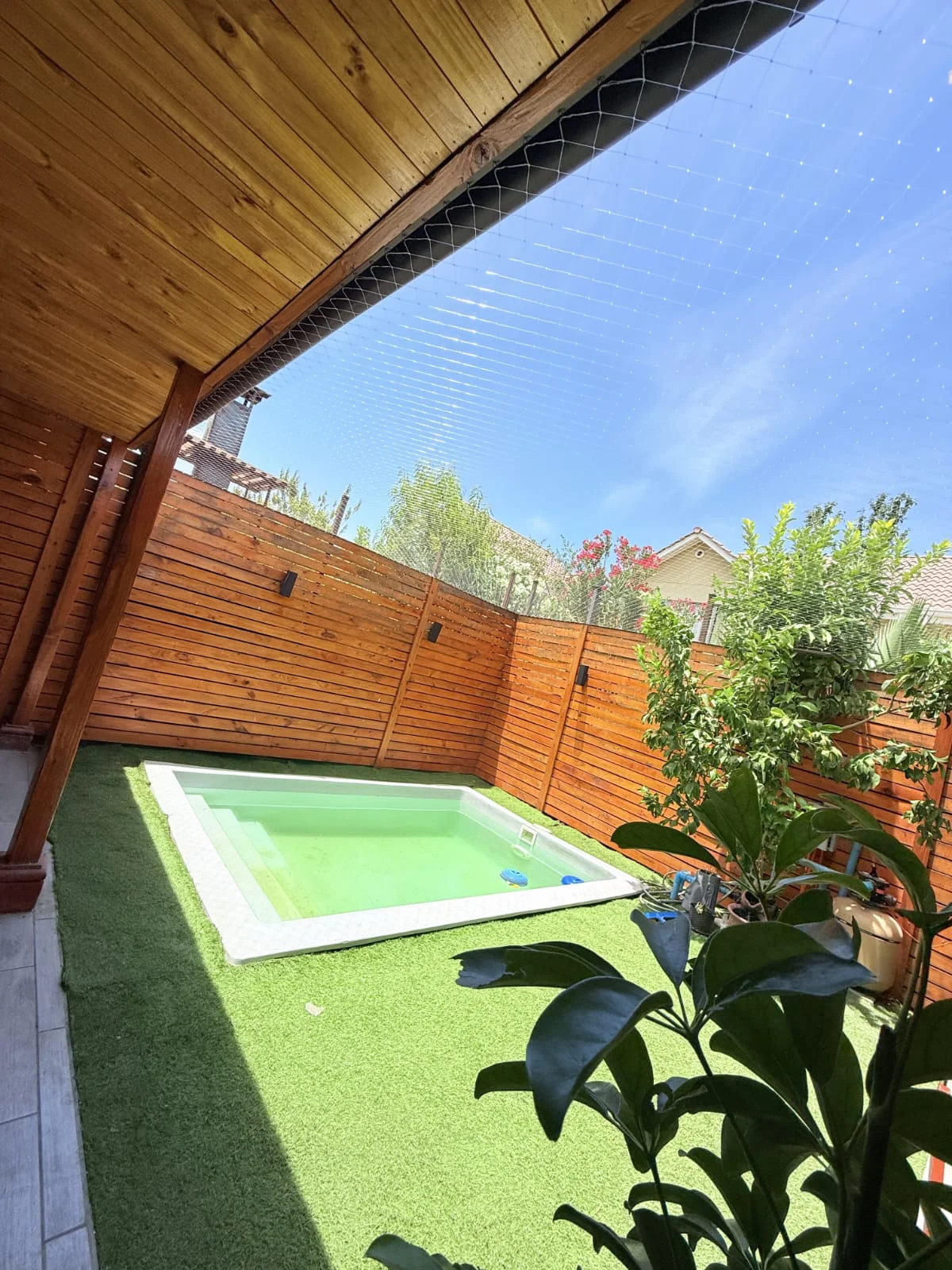 Terraza de madera con piscina y malla de protección superior